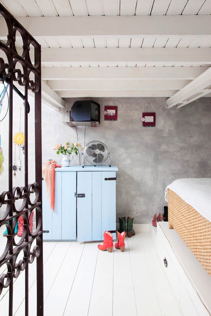 Bed on platform, black grille door and white wooden floor in bedroom