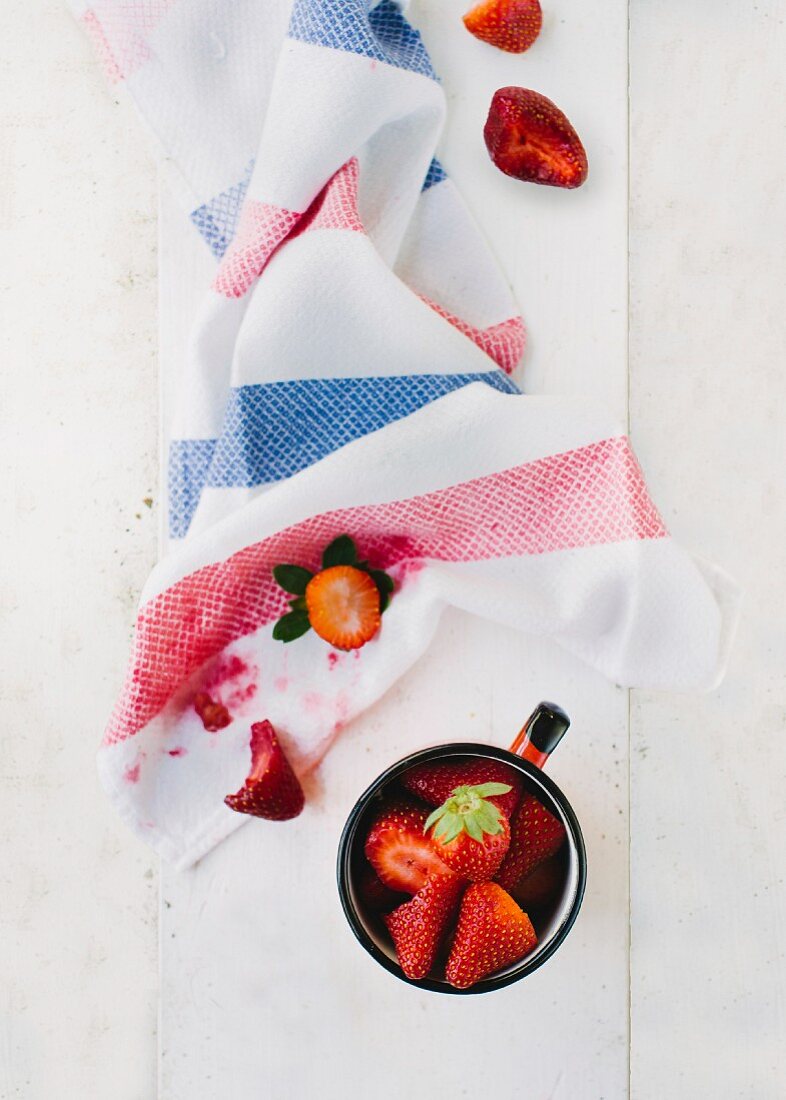 Fresh strawberries in a cup and on a tea towel