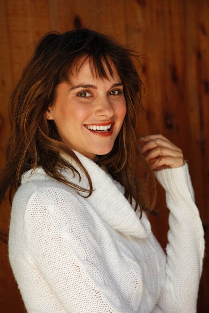 A brunette woman in a white knitted jumper with a cableknit pattern