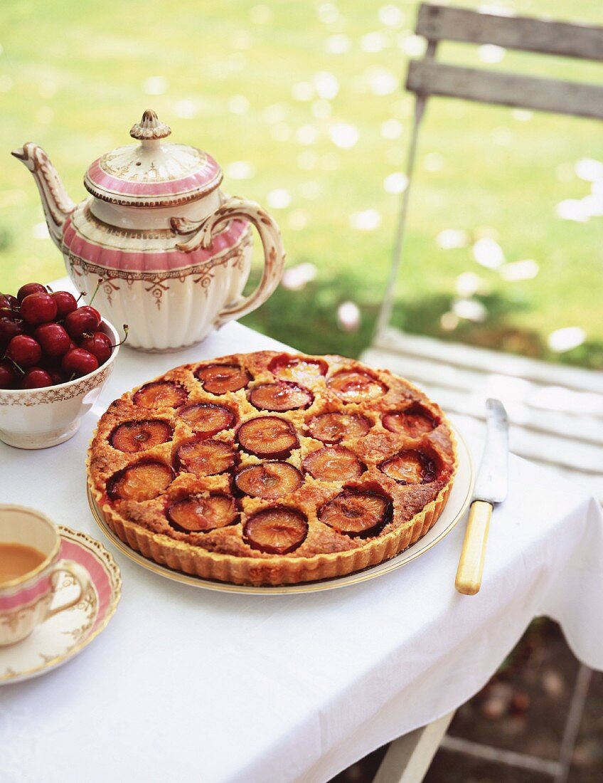 A coffee table in the garden with plum cake