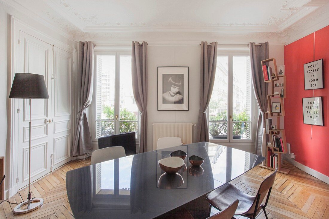 Dining area in restored period apartment with stucco ceiling and red accent wall