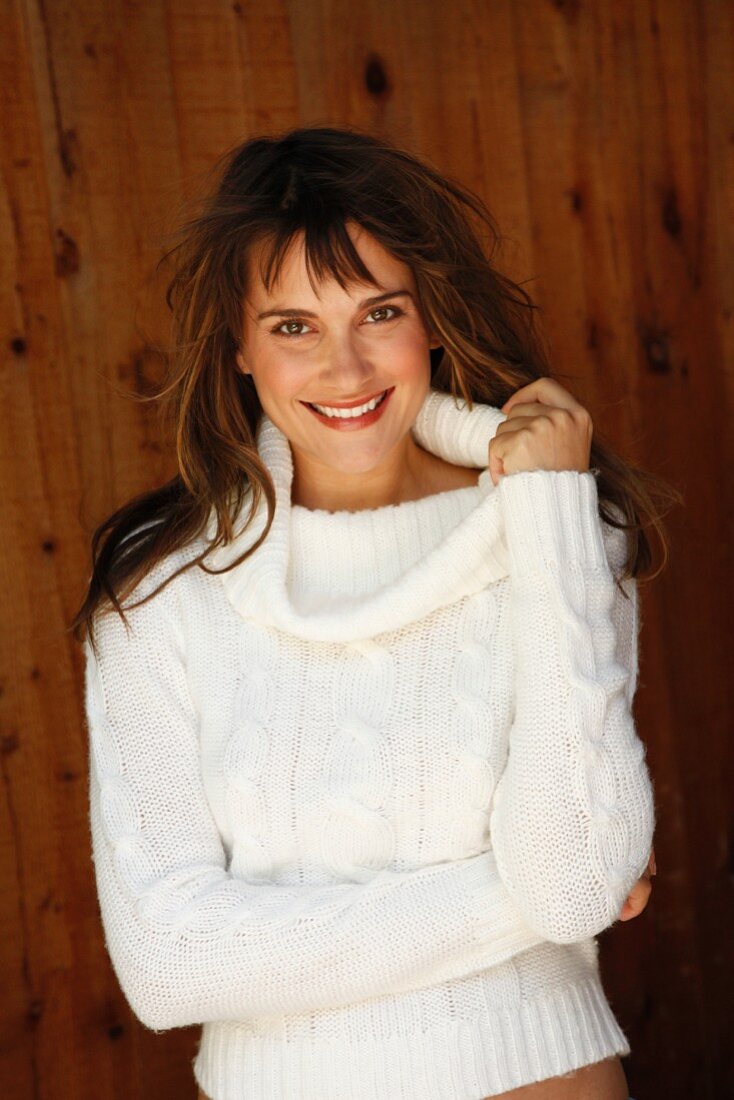 A brunette woman in a white knitted jumper with a cableknit pattern