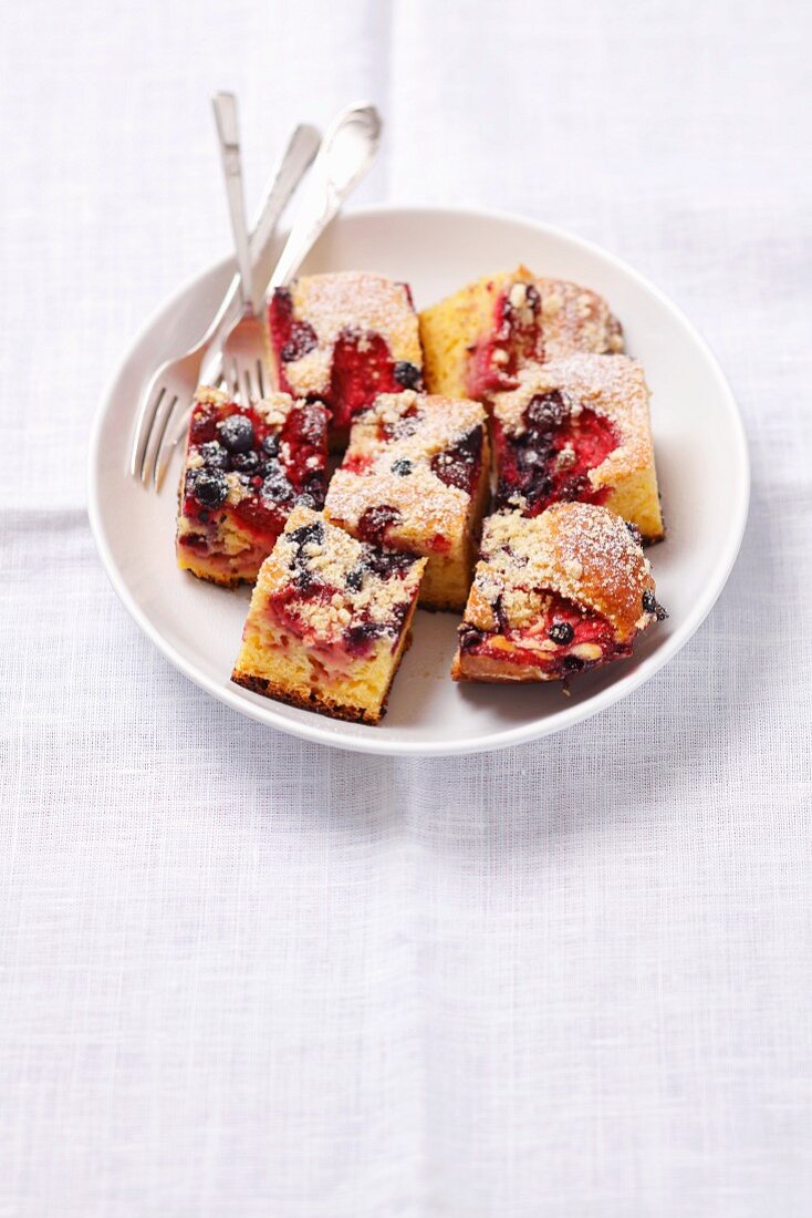Several slices of yeast traybake with berries on a plate