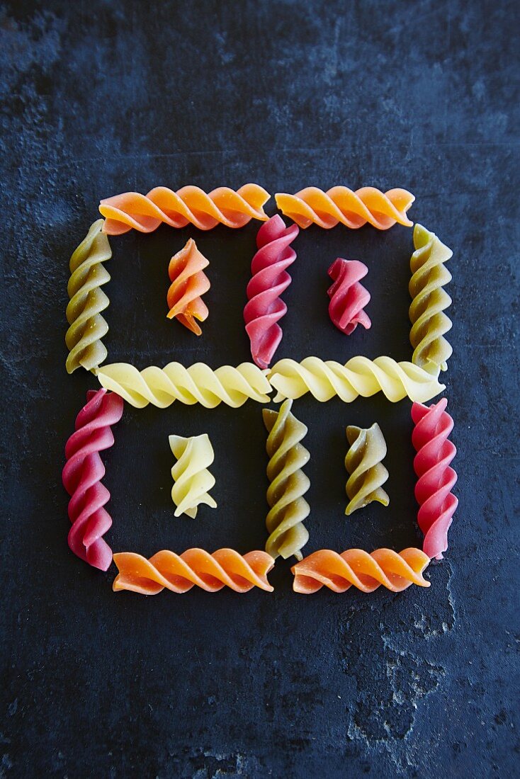 Colourful fusilli arranged to form a square pattern