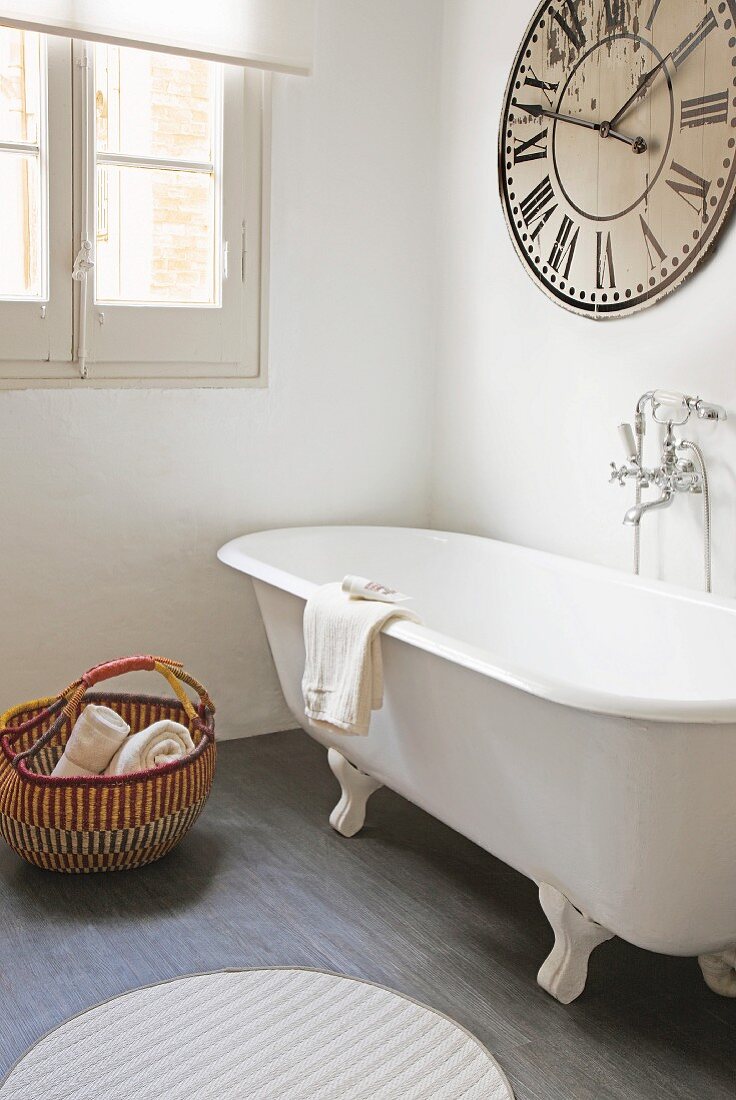 Free-standing bathtub and large vintage clock in bathroom