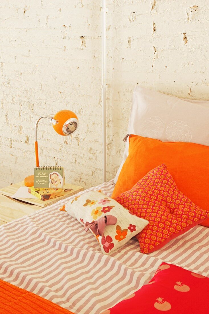 Orange pillows on bed and retro bedside lamp