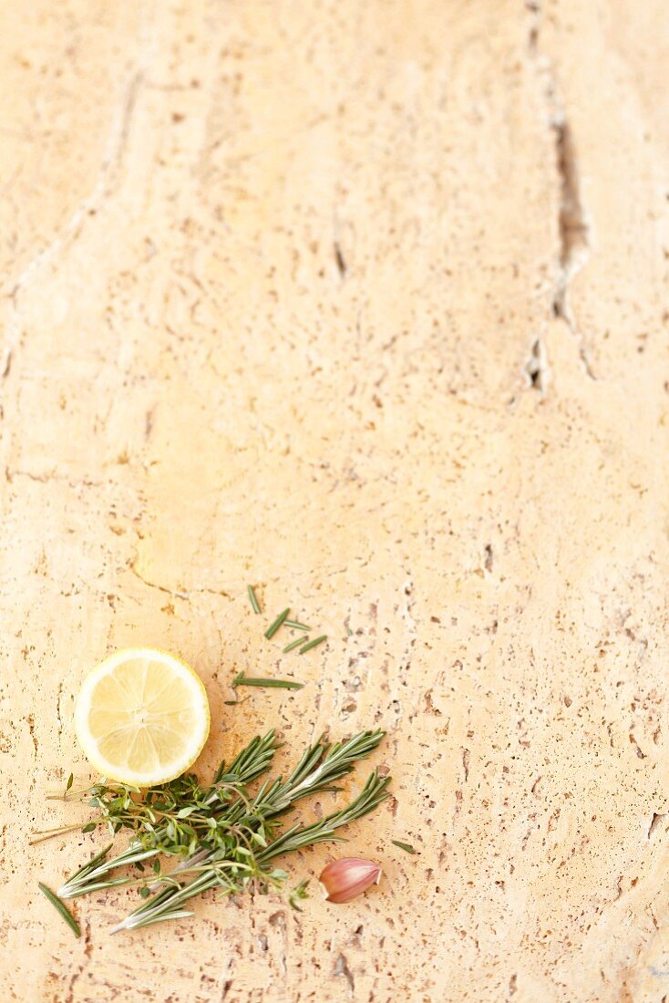 A stone background with lemon, garlic, rosemary and thyme