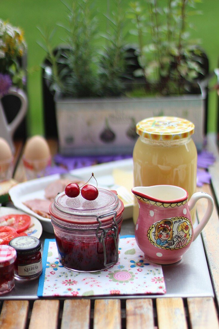 Frühstückstisch im Garten mit Marmelade, Wurst und Ei