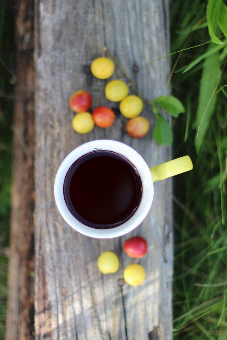 Kaffee und Mirabellen auf Holzbrett