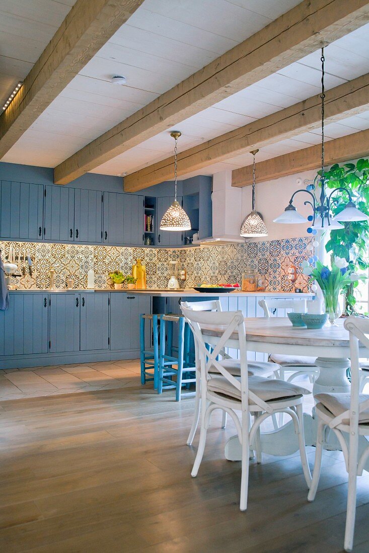 Cement tiles, kitchen counter and round dining table in open-plan country-house kitchen