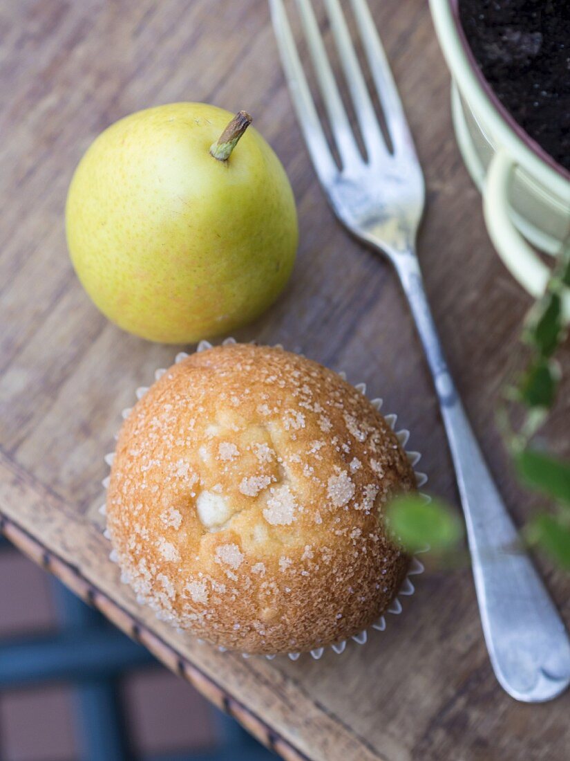 A Spanish Magdalena cupcake and a pear on a wooden table.