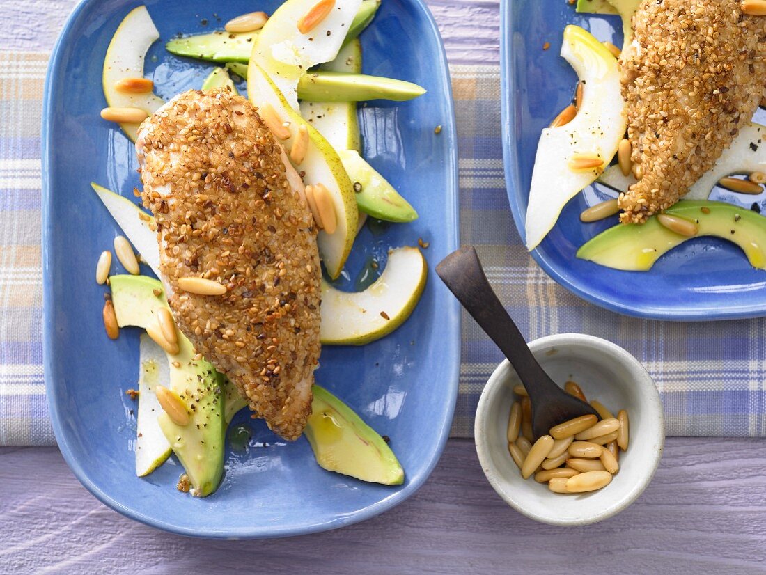 Chicken with a sesame seed coating on a bed of pear & avocado salad
