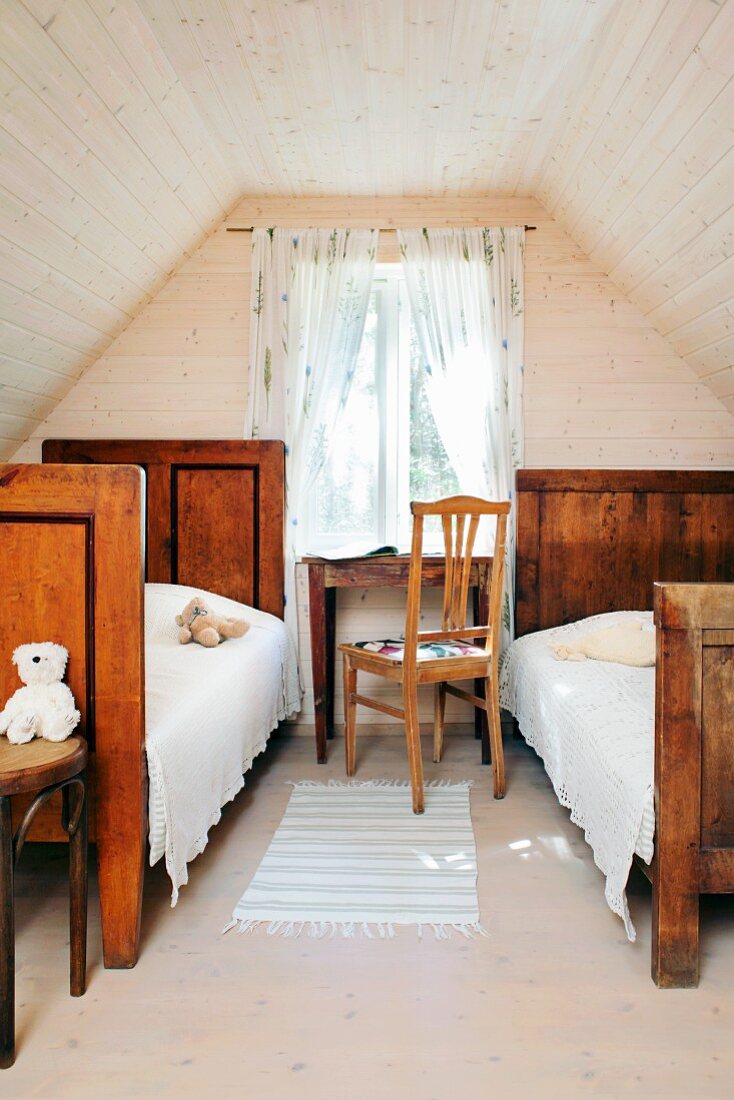Two old wooden beds in attic room with wood-clad walls