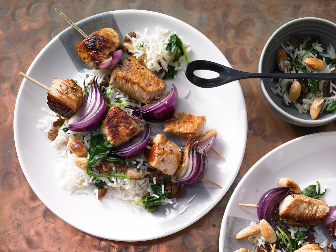 Turkey kebabs on a bed of spinach rice with almonds and rosemary