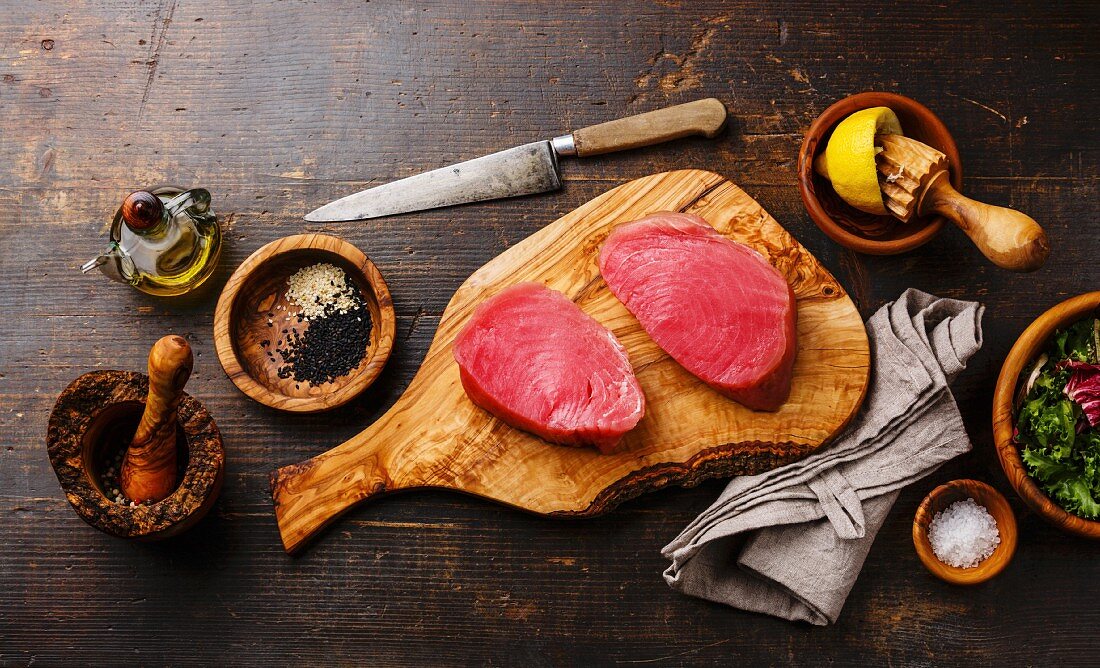 Raw tuna steaks fillet with lemon and sesame on olivewood cutting board