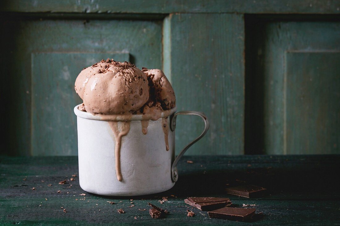 Frozen vintage aluminum mug with melting chocolate ice cream balls, served with chopped dark chocolate