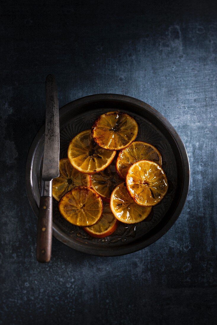 Candied orange slices on a plate with a knife