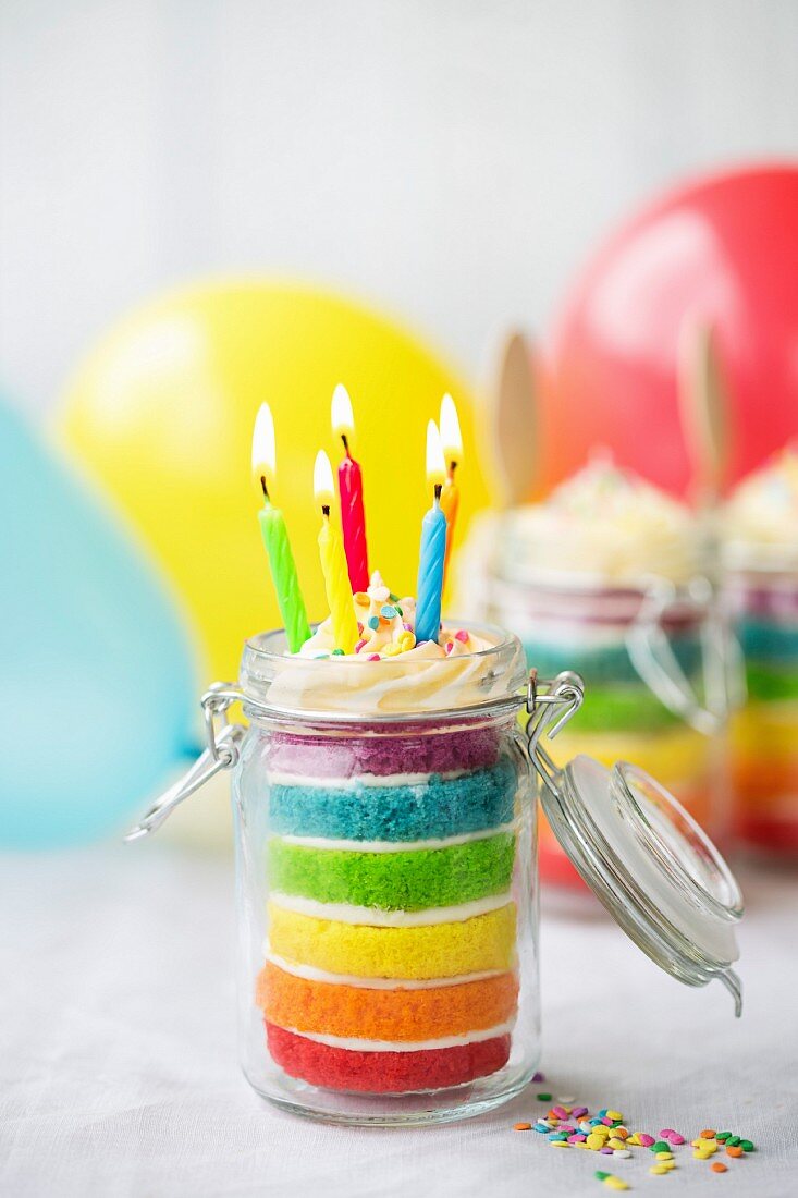 Mini Regenbogen-Schichtkuchen mit Geburtstagskerzen in einem Glas