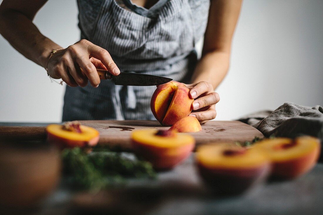 A woman s hands are photographed as she is slicing peaches