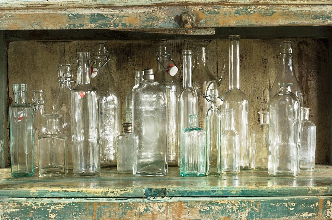 Various glass bottles in rustic kitchen cupboard