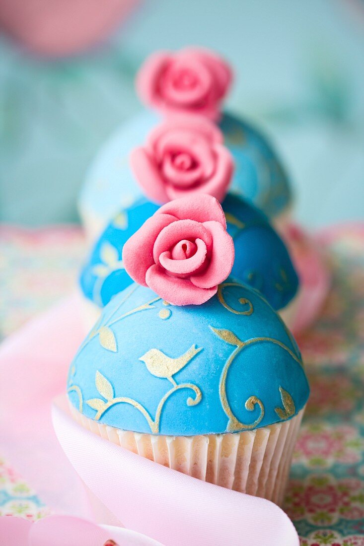 Cupcakes, verziert mit türkisfarbenem Fondant und rosa Zuckerrosen