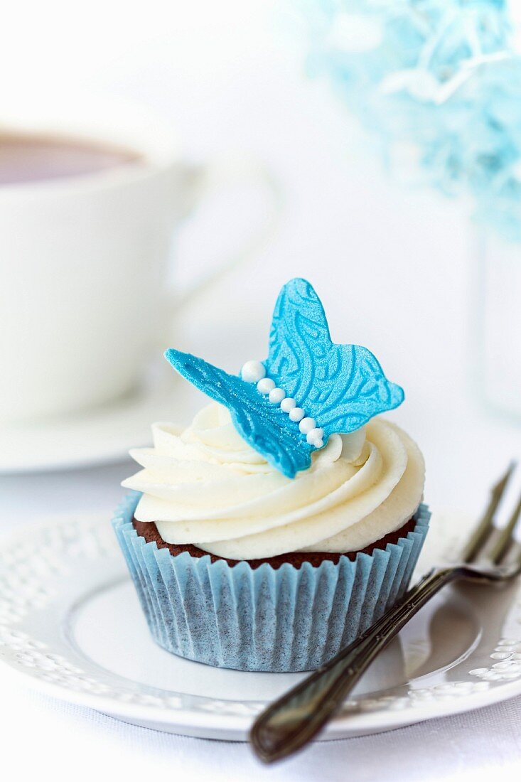 Schokoladen-Cupcake, dekoriert mit einem blauen Zucker-Schmetterling