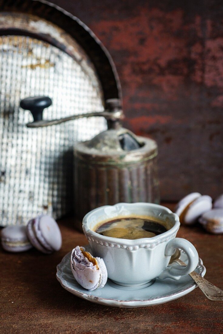 Selbstgemachtes Karamell-Macaron, angebissen und eine Tasse Kaffee