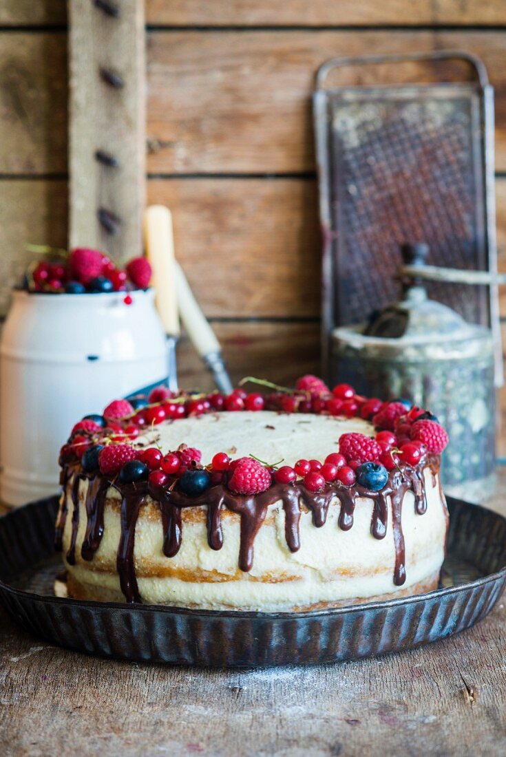 A semi-naked cake with vanilla cream, fresh berries and chocolate ganache