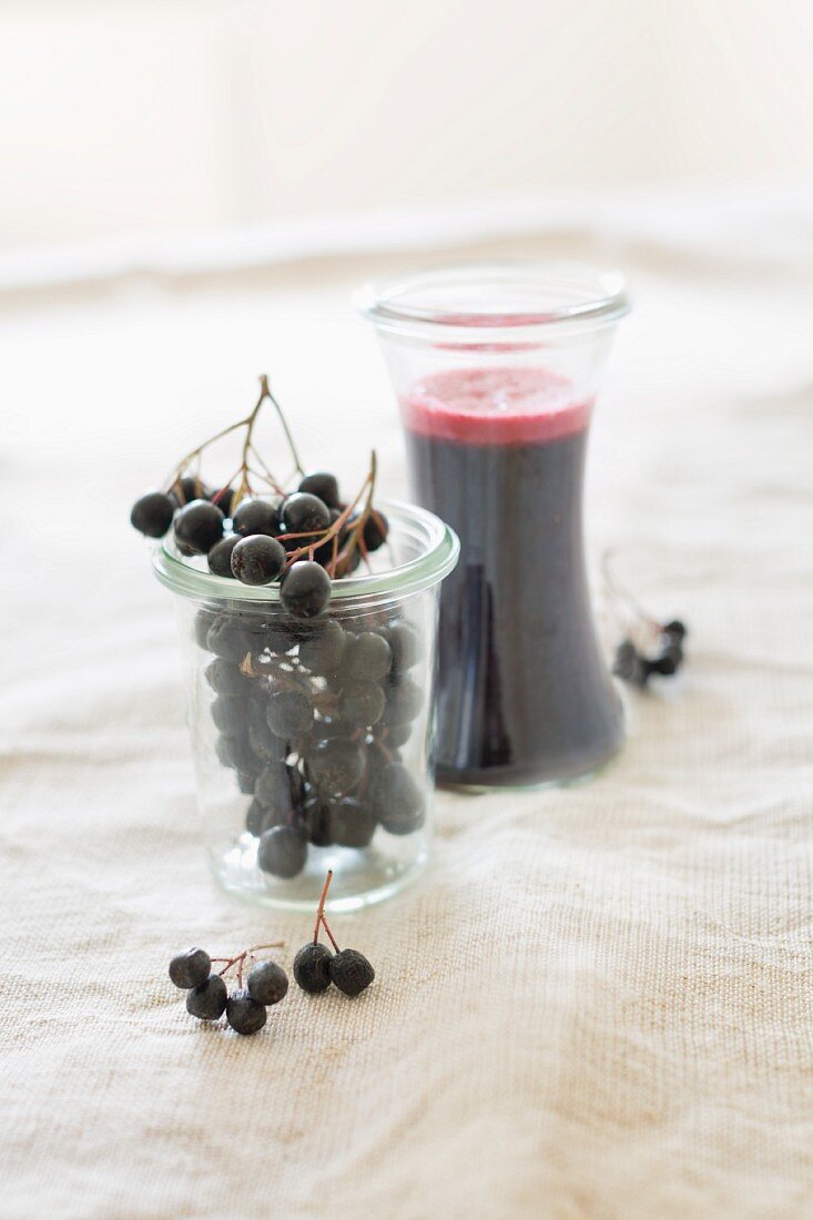 Fresh aronia berries and home-made aronia berry juice in glasses