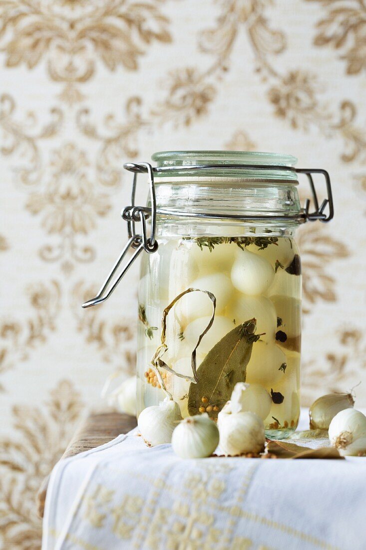 Pickled pearl onions with bay leaves, mustard seeds, pepper, white wine vinegar, sugar and herbs