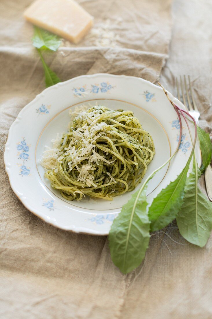 Spaghetti mit selbstgemachtem Löwenzahnpesto, frischen Löwenzahnblättern und Parmesan auf Leinentuch