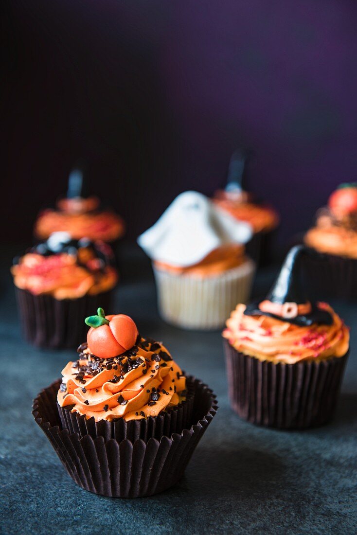 Halloween-Cupcakes mit orangefarbener Buttercreme und verschiedenen Fondant-Dekos