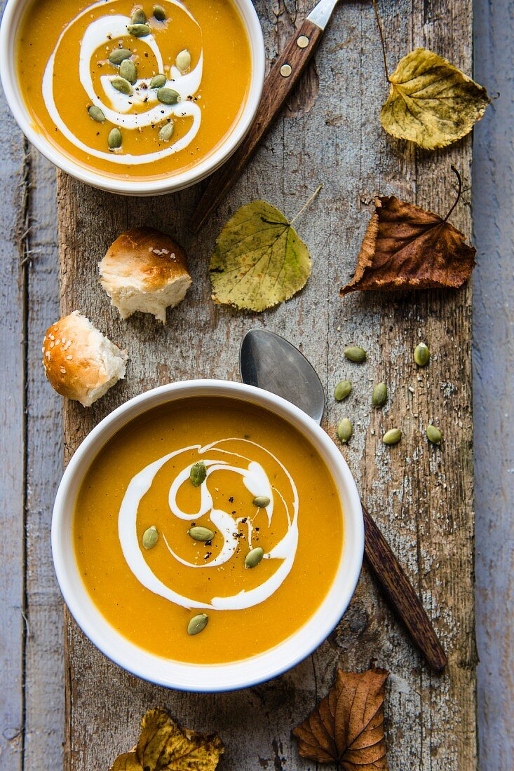 Creamy pumpkin with cream and pumpkin seeds on a wooden board