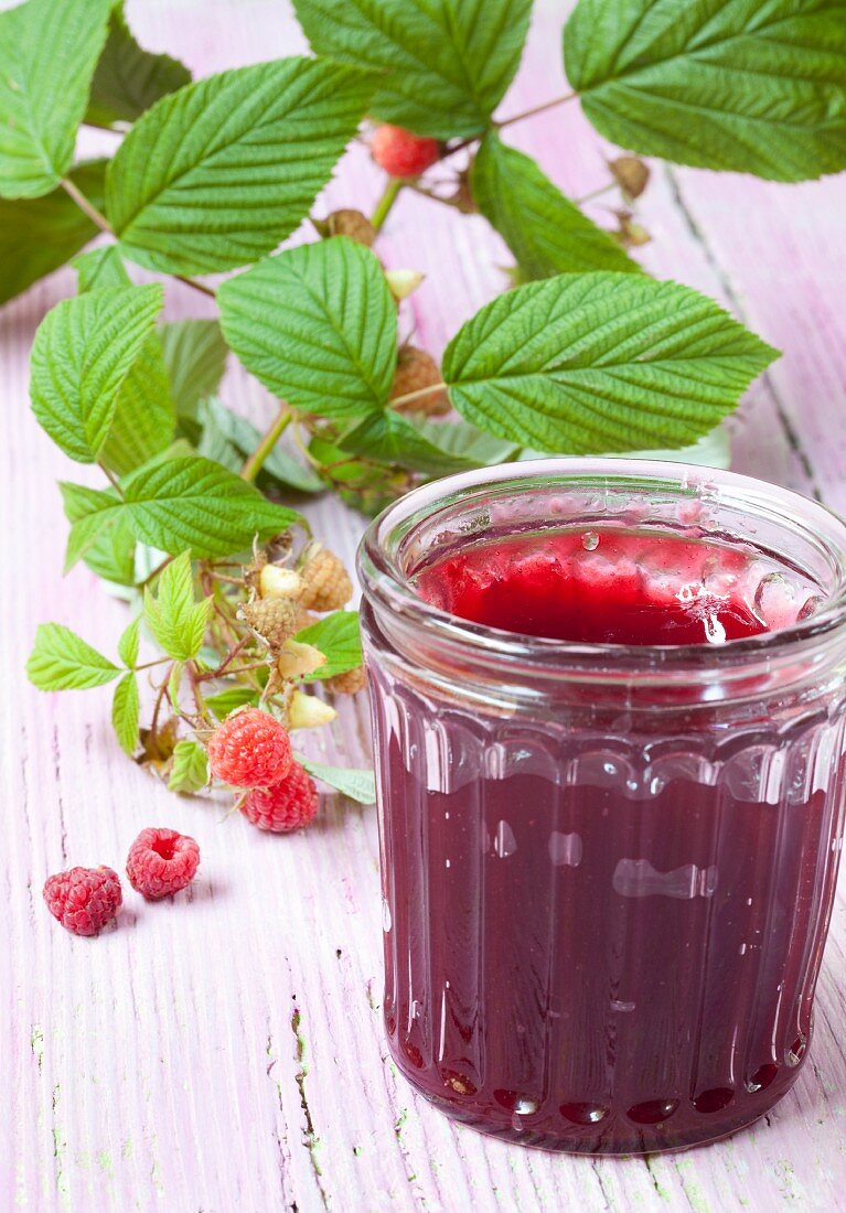 A jar of raspberry jam and fresh raspberries
