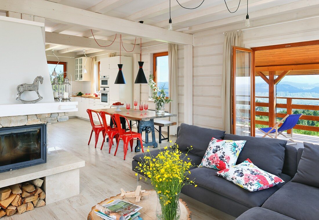 Sofa, dining table and open-plan kitchen in spacious interior of wooden house