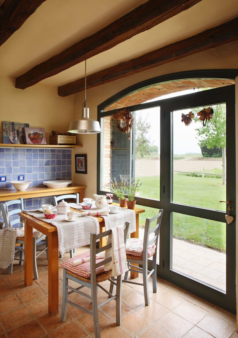 Set table and wooden chairs in dining area next to terrace doors with view of garden