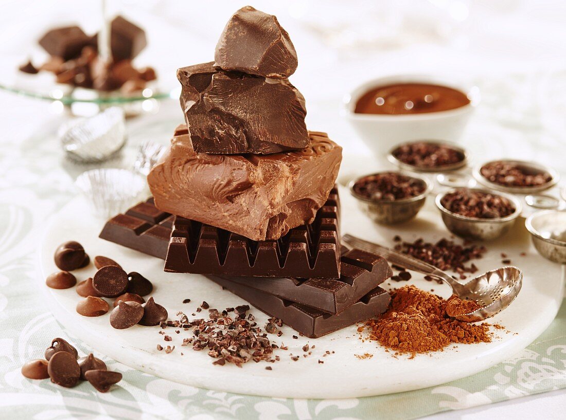 Verschiedene Schokoladenstücke, Chocolatechips, Kakaopulver und Kakaonibs