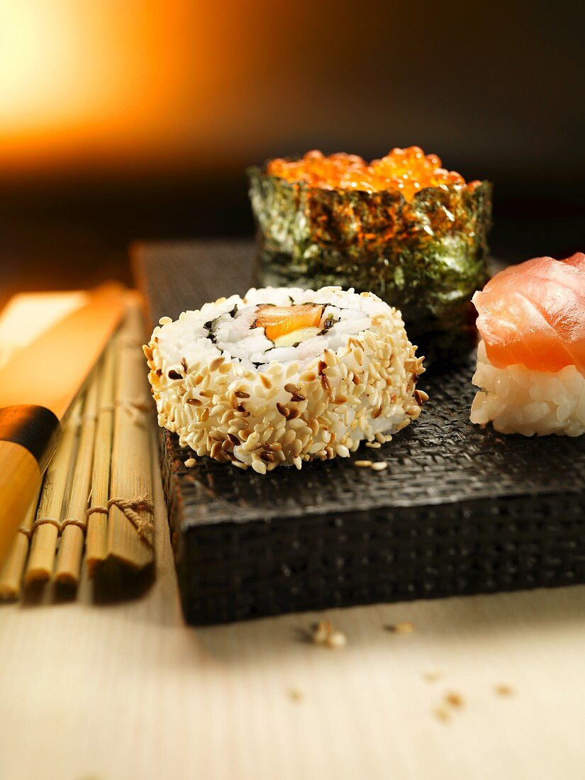 Verschiedene Sushi auf schwarzem Brett