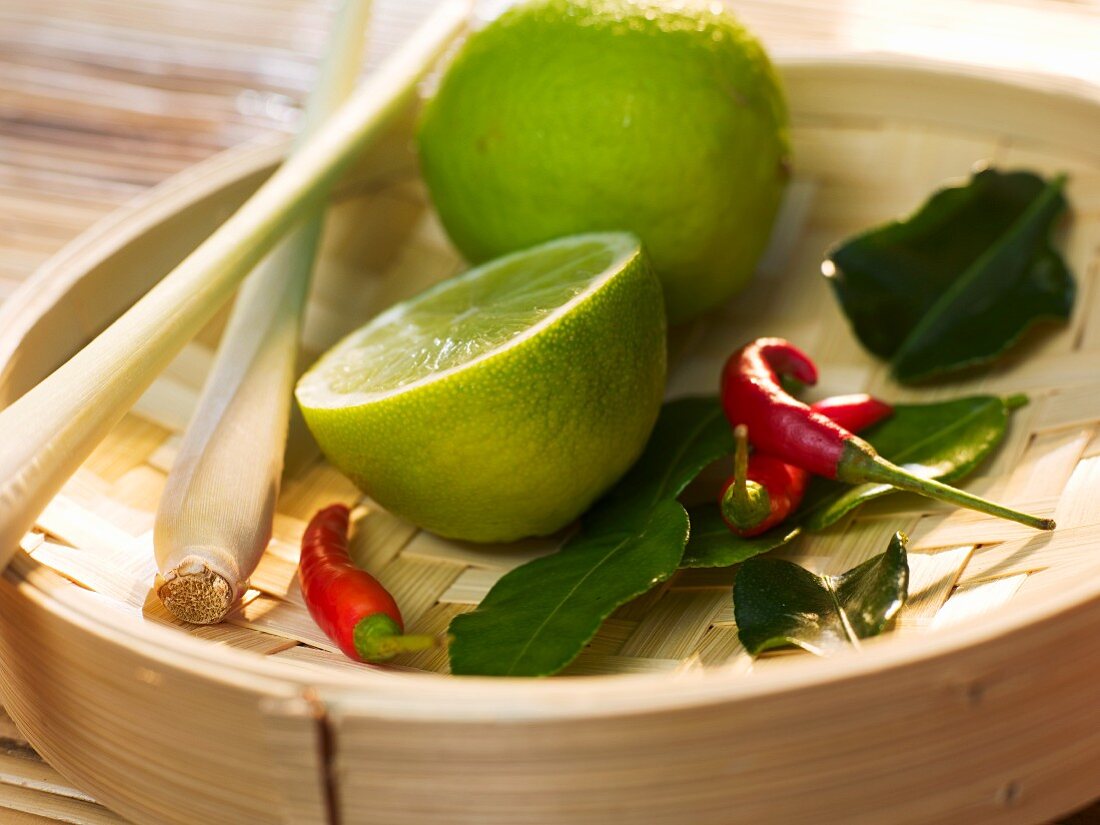 Zitronengras, Limetten, Zitronenblätter und Chilischoten auf Bambusdämpfer