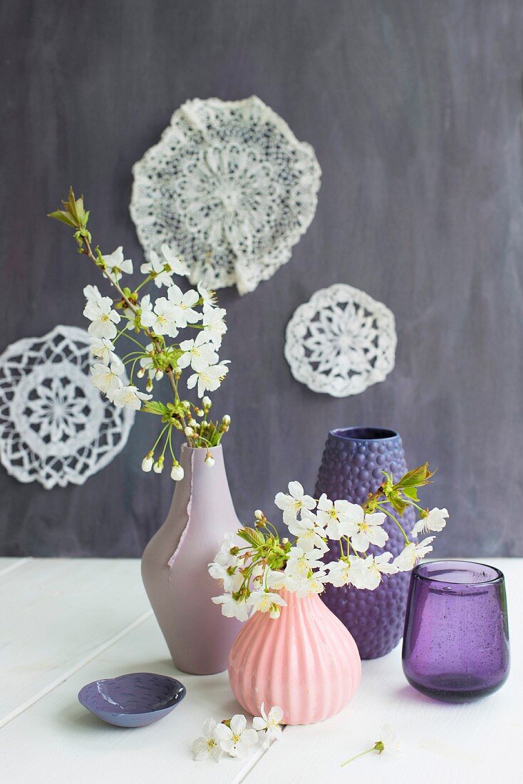 Flowering branches in vases with structured surfaces in various shades of pink and purple