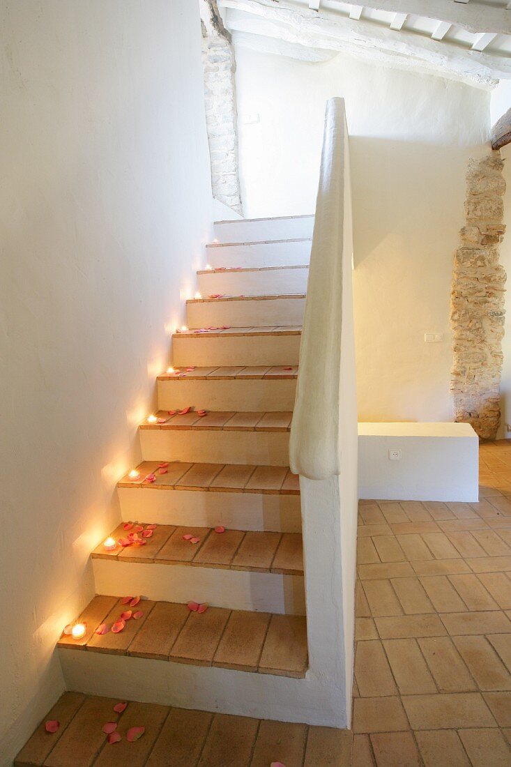 Mit Teelichtern und Rosenblütenblättern romantisch dekorierte Treppe in restauriertem historischem Gebäude