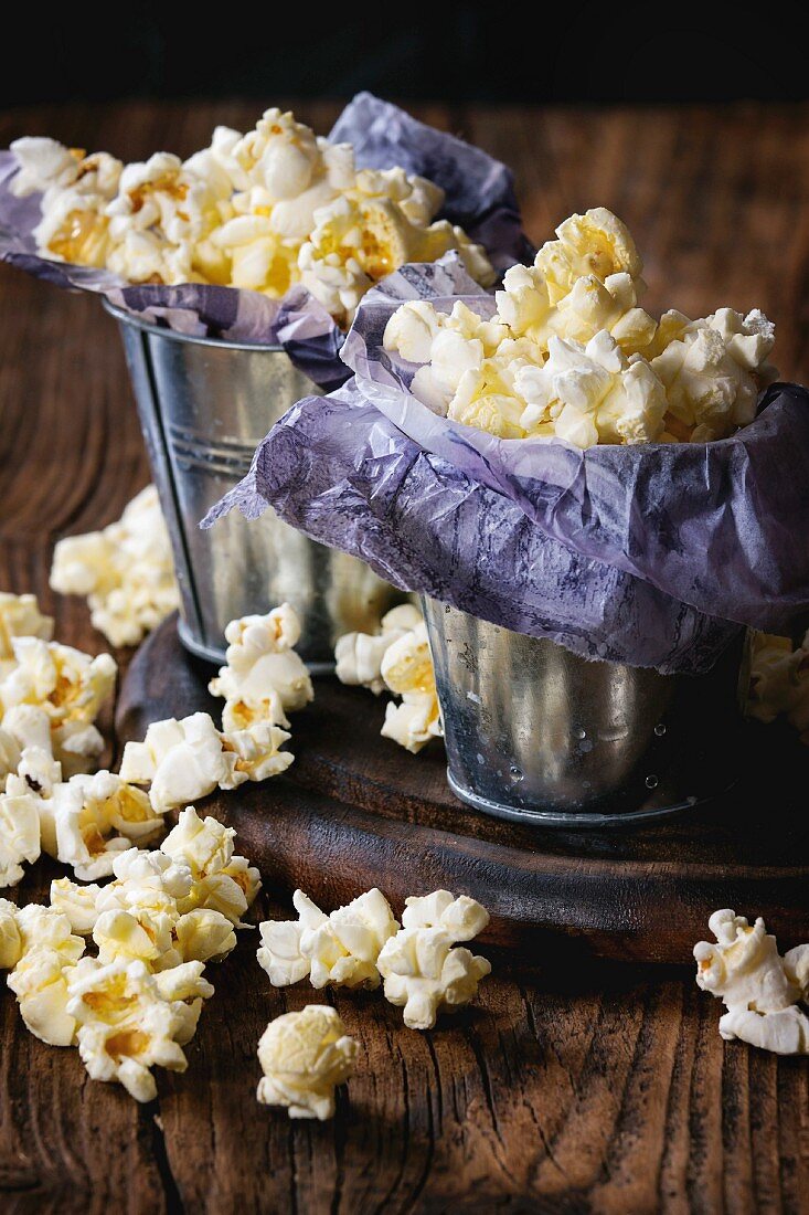Gesalzenes Popcorn serviert in kleinen Eimern mit lila Papier