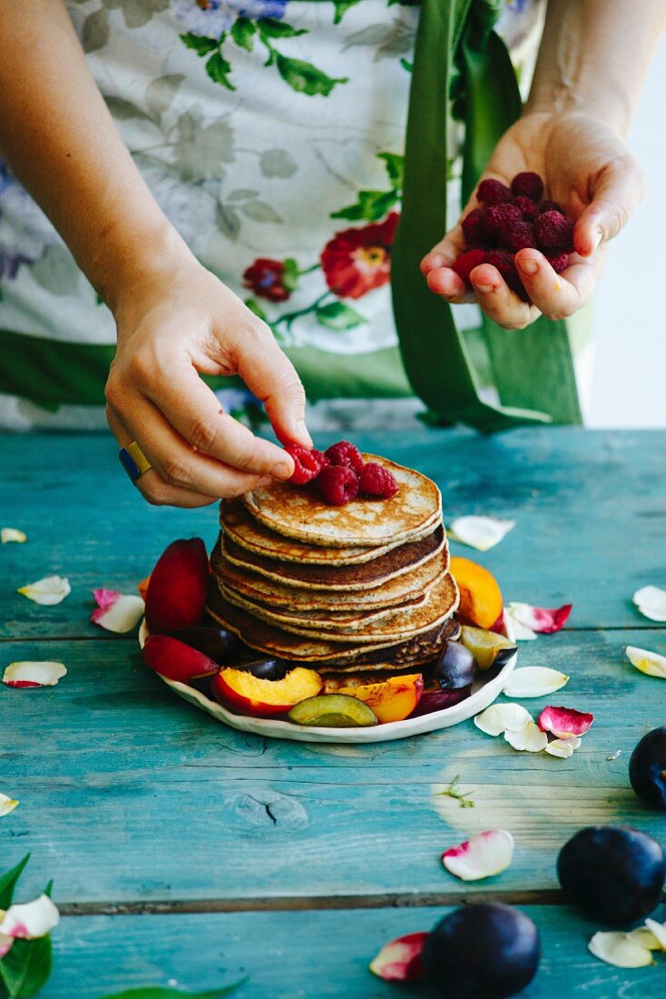 Girl putting raspberries on the top of pancakes