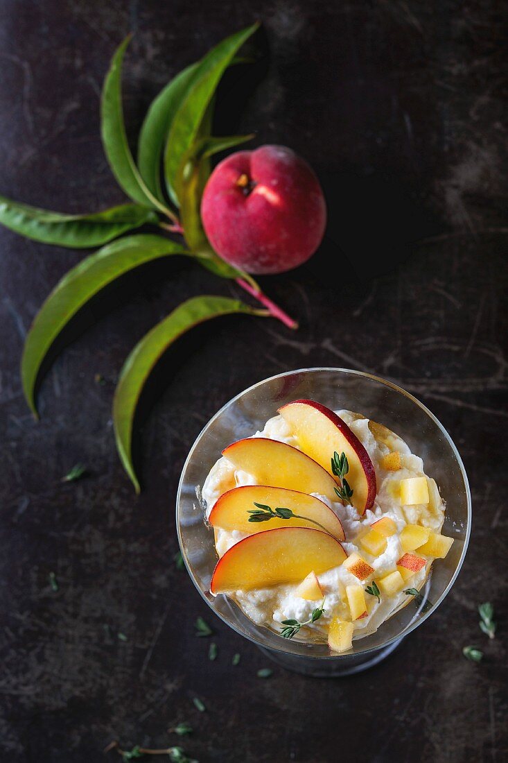 A ricotta dessert with peach, thyme and honey served in a cocktail glass