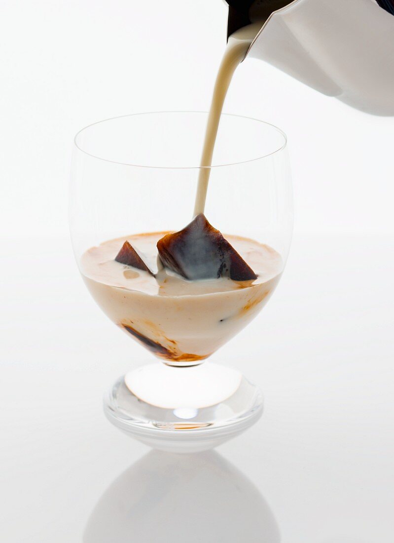 Eiskaffee in Glas gießen