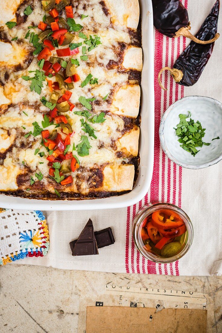 Enchiladas mit Schweinefleisch und Mole in Auflaufform mit eingelegten Jalapenos