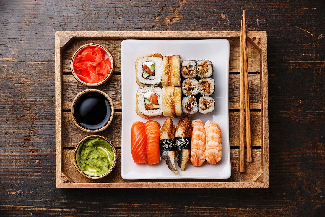 Verschiedene Sushi (Nigiri und Maki) Essstäbchen, Ingwer, Sojasauce und Wasabi auf Holztablett