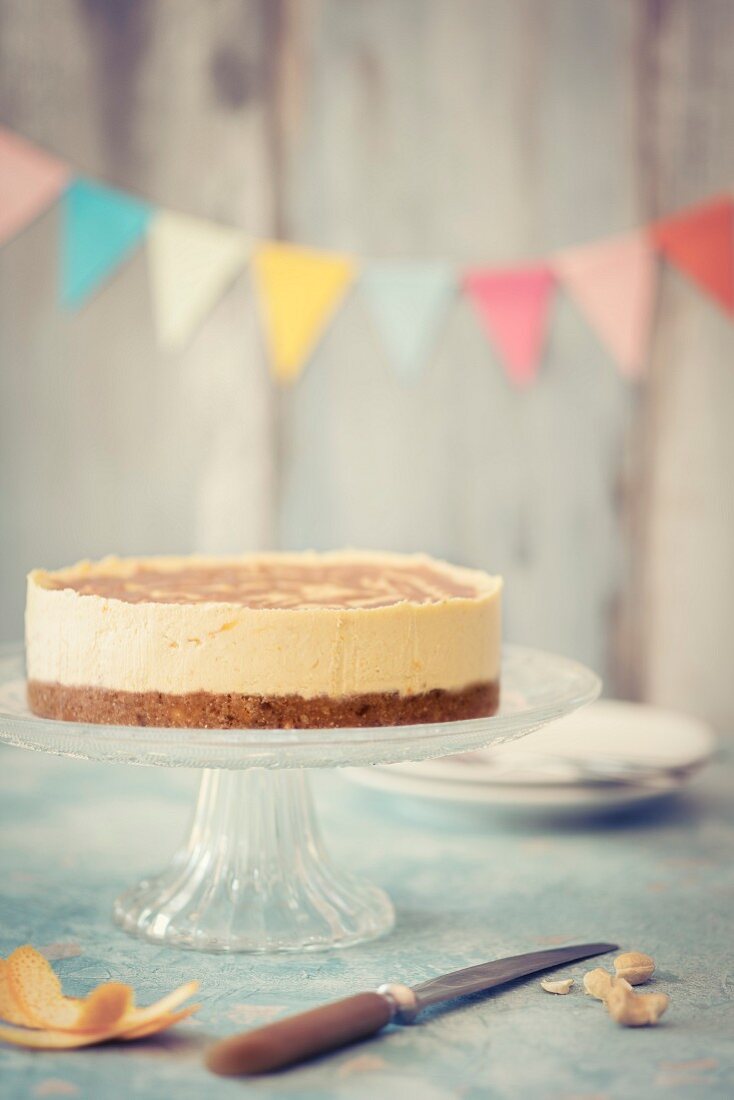 Veganer Käsekuchen (RAW-Küche) auf Tortenständer, im Hintergrund Wimpelkette