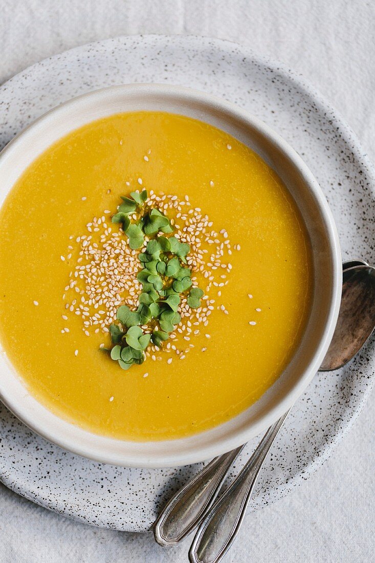 Kabocha-Kürbis-Suppe, garniert mit Sesam und Keimlingen