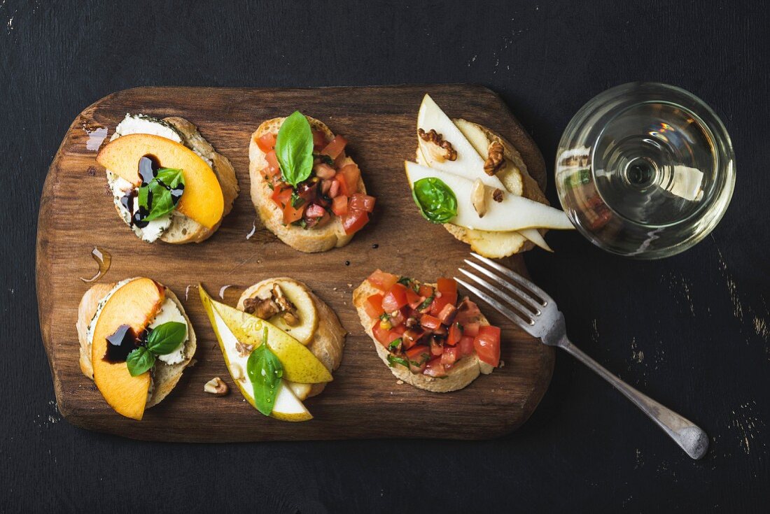 Bruschetta mit Früchten und mit Tomaten und ein Glas Weißwein